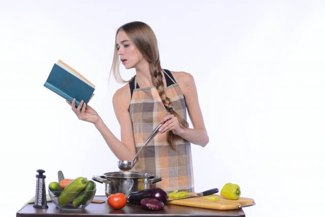 レシピを見ながら料理をする女性